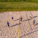 Trening siatkarek na boisku do siatkówki plażowej. Widok z drona.