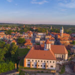 Widok na mury miejskie i stare miasto w Kożuchowie z drona. W centralnym miejscu zdjęcia zamek. Piękna, słoneczna pogoda.